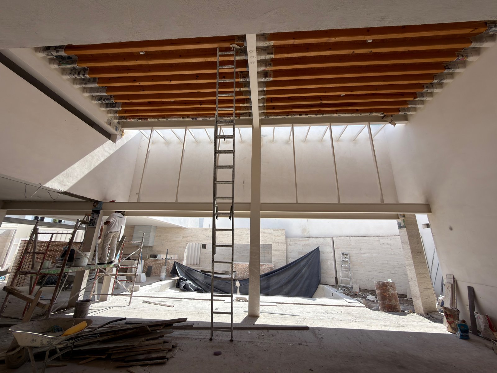 Obra con vigas de madera protegidas y estructura y muros con acabado en tono claro.